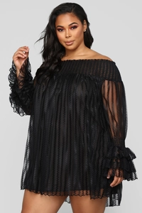 Détail de robe noire en dentelle à épaules dénudées avec texture vague et volants