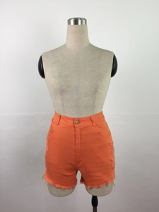 Détail d'un short en jean orange taille haute avec déchirures usées et ourlets effilochés