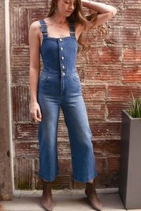 Detail of slim fit denim jumpsuit featuring metal buttons and adjustable straps