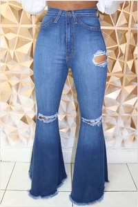 Close-up detail of high-waisted wide leg flared jeans with ripped knees and raw hem edges