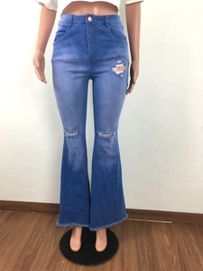Detail view of high-waisted flared jeans with distressed knee rips and raw fringe hems