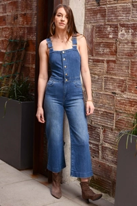Detail of slim fit dark blue denim jumpsuit with metal buttons and adjustable straps