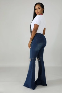 Detailed back view of high-waisted flared jeans with ripped knees and raw hem edges