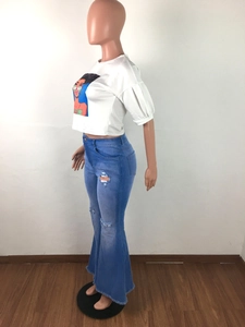Detail view of high-waisted distressed bell-bottom jeans with raw hem and knee holes
