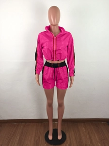Detail van neonroze trainingspak met ritsjack en short voorzien van zijstrepen