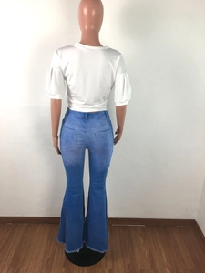 Detail view of high waist flared jeans with frayed hem and rear pockets on a mannequin