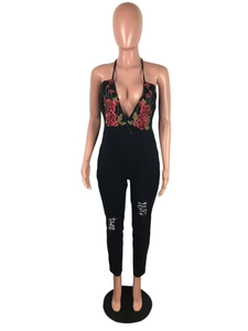 Detail of floral embroidery and deep V-neck on a black halter neck denim jumpsuit