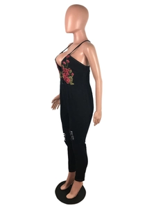 Detail of red floral embroidery on black backless denim jumpsuit with distressed knee rips