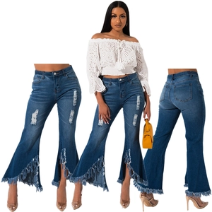 Detailed close-up of distressed denim flare jeans with raw frayed hems and side slits