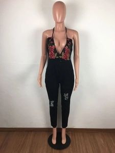 Detail of floral embroidery on a black halter-neck jumpsuit with distressed knee rips