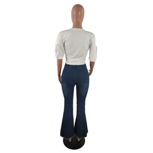 Rear view of high waisted dark blue flared jeans with raw hem and white puff sleeve top