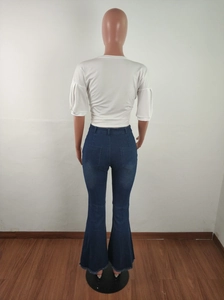 Detail view of bell-bottom jeans with frayed hems and back pockets on a mannequin