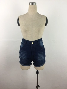 Detail of high-waisted denim shorts featuring vintage wash and gold button closure