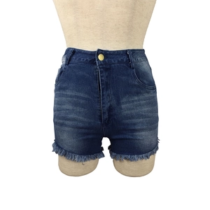 Detail of high waisted blue denim shorts featuring frayed edges and vintage washed whiskers