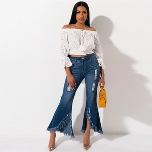 Detail of high-waisted wide leg flared jeans featuring distressed knees and raw fringe hems