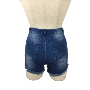 Detail view of high-waisted denim shorts featuring frayed hems and vintage washed finish
