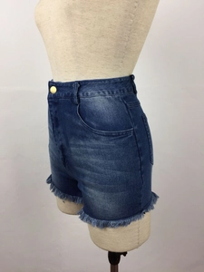 Detail of high-waisted distressed denim shorts with golden button and frayed hem edges