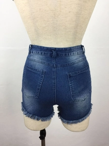 Detail view of high-waisted denim shorts back pockets and frayed tassel hem in dark blue
