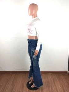 Detail of blue high-waisted flared jeans featuring distressed rips and frayed hem design