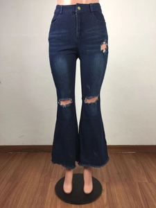Détail du jean évasé taille haute avec trous usés et ourlet brut effiloché