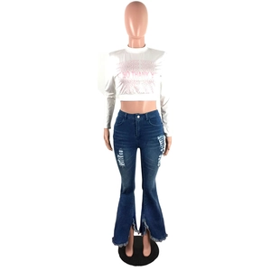 Detail of high waisted flared jeans with knee distressing and frayed slit hem