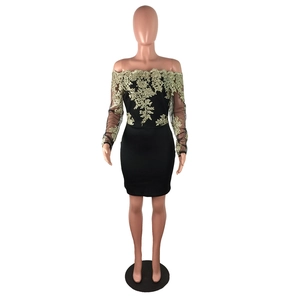Détail de la broderie florale dorée sur les manches en maille noire de la robe