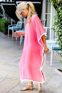 Détail de la robe de plage en mousseline rose avec finitions à pompons blancs et glands