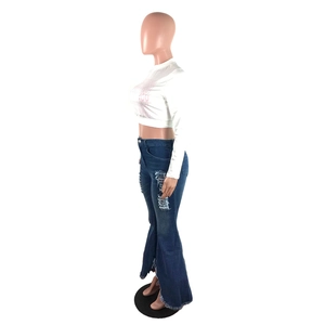 Detail showing distressed ripped knees and faded texture on dark blue flared denim jeans