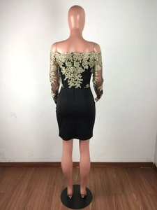 Détails de broderie florale dorée sur les manches en dentelle noire d'une robe de soirée