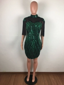 Macro detail of emerald green sequins and black fringe on a slim fit party dress