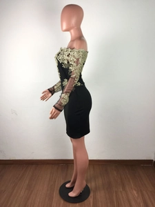 Détail de la broderie dorée et des manches en maille transparente sur une robe noire sexy