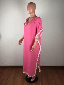 Détail de la tunique de plage rose bohème avec bordure à pompons blancs et col en V ample