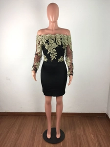 Détails de la broderie complexe de dentelle florale dorée sur une robe courte ajustée