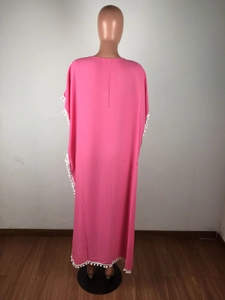 Détail du dos du caftan en mousseline rose avec bordure de pompons blancs sur l'ourlet