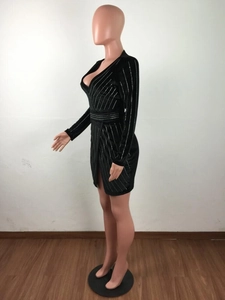 Détail d'une robe moulante noire avec col en V profond et motifs en strass argentés