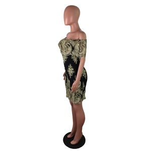 Détail d'une mini-robe noire à épaules dénudées avec broderie en dentelle dorée