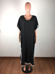 Détail de la tunique de plage noire ample avec bordure à pompons blancs et pompons