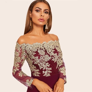 Détail de la robe bordeaux à épaules dénudées avec broderie dorée et manches en résille