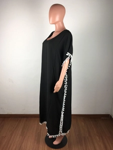Détails de la tunique de plage en mousseline noire avec pompons blancs et col en V
