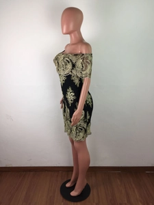 Détail de la robe noire à épaules dénudées avec broderie florale dorée élégante