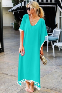 Détail de la tunique de plage turquoise avec col en V et bordures à pompons blancs