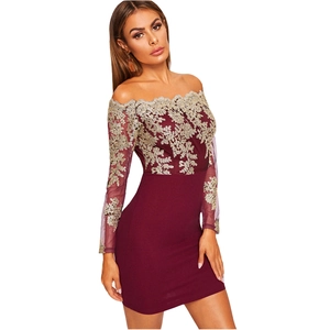 Détail de dentelle florale dorée sur robe rouge vin à épaules dénudées et manches longues