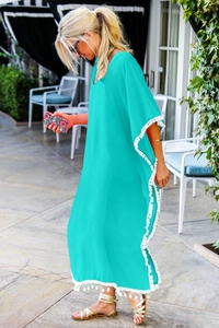 Détails des pompons blancs et pompons sur un cache-maillot de plage turquoise à col en V