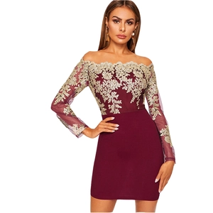 Détails de broderie en dentelle dorée sur une robe bordeaux à manches longues et épaules nues