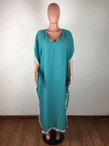 Détail de la robe de plage en mousseline sarcelle avec bordure à pompons blancs et col V