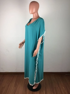 Détail de la robe de plage bleue en mousseline avec des pompons blancs sur le col en V