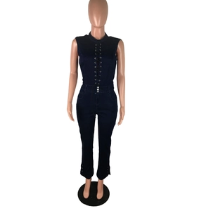 Detailed close-up of metal eyelets and lace-up design on dark blue denim jumpsuit