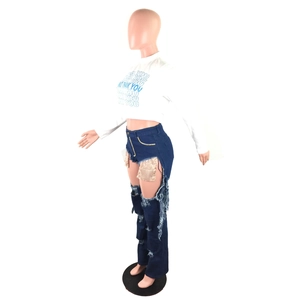 Detail of high-waisted distressed blue jeans with sparkling sequin mesh inserts and rips