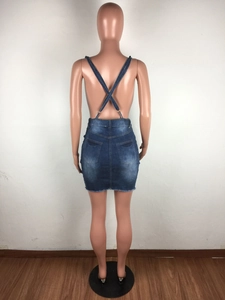Detail view of denim mini dress featuring cross-back straps and frayed fringe hemline