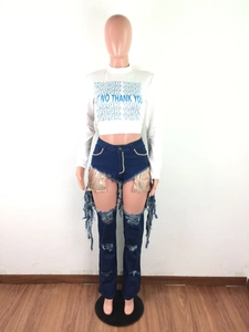 Detail of high waist denim jeans featuring ripped cut-outs and gold sequin tassel accents